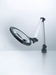Preview: The image shows a flexible magnifying lamp with a large, round light ring. It stands on a stable base and has an adjustable arm that positions the lamp in various orientations.