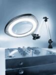 Preview: The image shows a magnifying lamp with ring lighting mounted on a table. Below it is a metallic component with various small tools or structures.