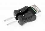Preview: The image shows a black plug with a rectangular connection on top and two metallic pins protruding from the sides. The surface is ribbed and there are small screws.