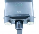 Preview: The image shows a Mantis IOTA, a compact, portable visual aid device. It has a gray surface with round lenses and a sturdy base. Ideal for improved vision for near and distant objects.