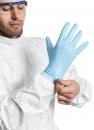 Preview: Ein Mann in einem weißen Schutzanzug zieht sich einen blauen Gummi-Handschuh an. Er trägt eine Schutzbrille und konzentriert sich auf die Aufgabe.