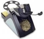 Preview: The image shows a small, black and gray metal sharpener with a holder on top for pencils. On the side, there is a container for wood shavings. A lever allows for the turning of the pencil.