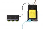 Preview: The image shows a security device with a black casing and a yellow label. It has a cable connection to a control box with three buttons that light up green.