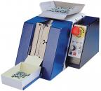 Preview: The image shows a blue machine with two funnels on top that dispenses small parts. On the side, there is an emergency stop switch and a control panel with buttons. The machine stands stable on a surface.