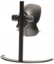 Preview: The image shows a black, round computer camera attached to a sturdy, vertical holder. The holder has a curved base. The camera lens faces forward.