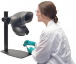 Preview: A person in a white lab coat with green gloves is examining something with tweezers. In front of them is a black device that looks like a microscope.
