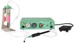 Preview: The image shows a medical device. It has a green casing with a pressure gauge and switches. A hose leads to a handpiece with a fine nozzle, next to it there is a foot pedal and a container with liquid.